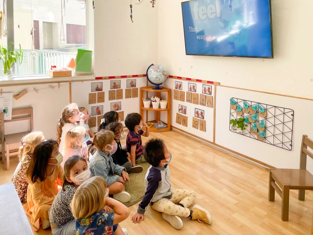 a classroom of children watching a tv screen